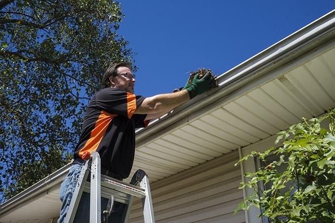 a worker using a ladder to fix a damaged gutter in Chatsworth